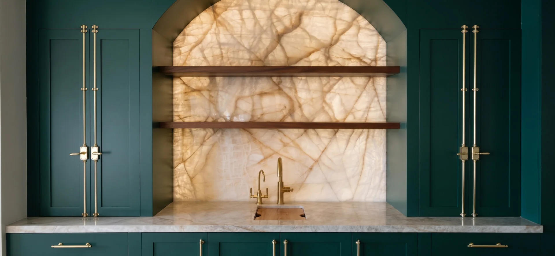 Backlit onyx wet bar with green cabinetry and brass fixtures